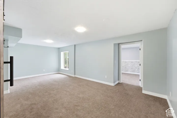 Expansive carpeted room featuring light blue walls, white trim, and a window