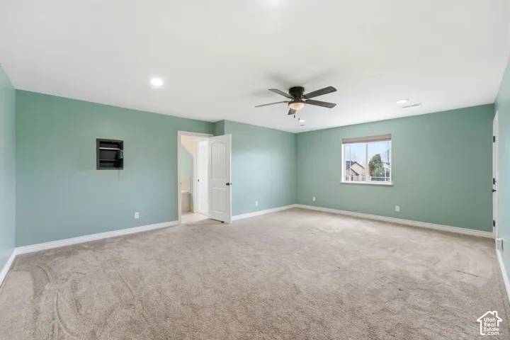 Spacious room featuring light green walls and neutral-toned carpet