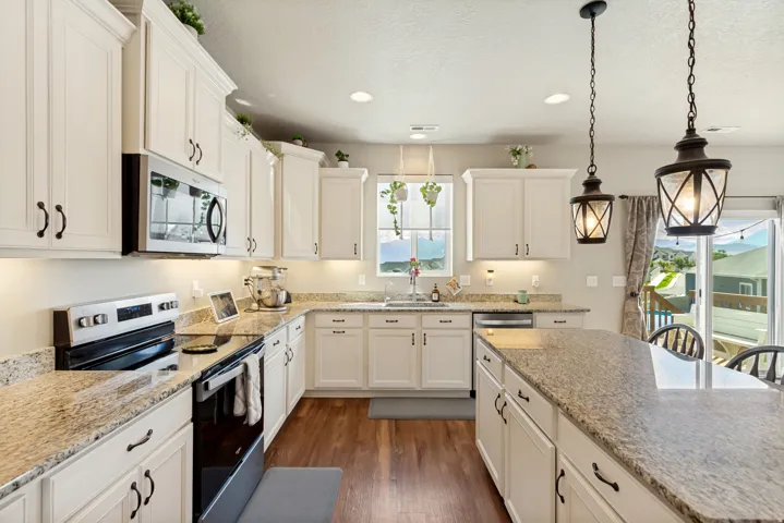 Kitchen featuring white cabinetry, granite countertops, stainless steel appliances, and pendant lighting over a central island
