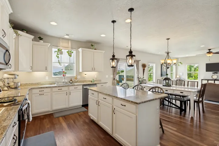 Open-concept kitchen featuring an island with granite countertops, recessed lighting, and white cabinetry