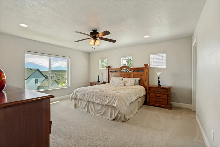 Carpeted bedroom featuring a ceiling fan with integrated lighting, recessed lighting, and multiple windows