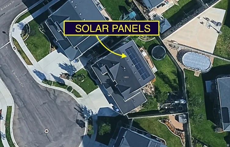 Property featuring solar panels, a substantial asphalt shingle roof, green landscaping, and a concrete driveway