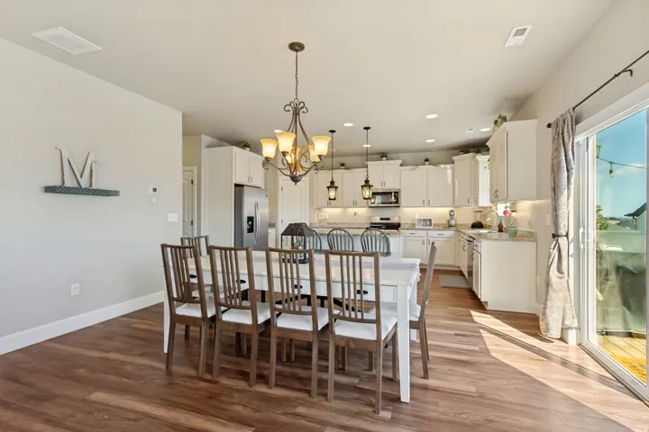 Open-concept kitchen and dining area featuring white cabinetry, recessed lighting, and a sliding glass door leading to an outdoor space