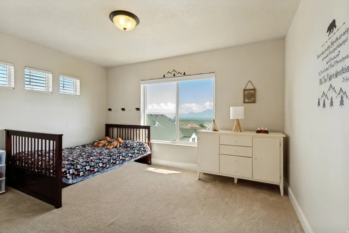 Bright interior space featuring a large window with distant mountain scenery, three high-set windows, a neutral carpeted floor, and a semi-flush mount ceiling light fixture