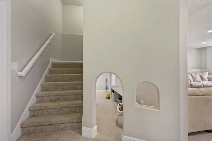 Carpeted staircase with white handrail and baseboards
