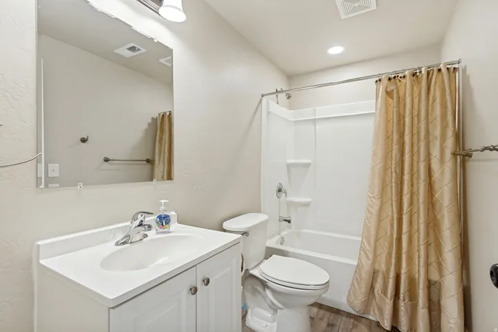 Bathroom featuring a vanity with integrated sink, rectangular mirror, and a shower-over-tub combination with a white surround