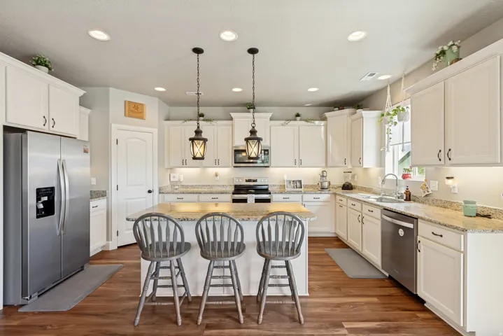 Modern kitchen featuring white cabinetry, granite countertops, and wood-finish flooring