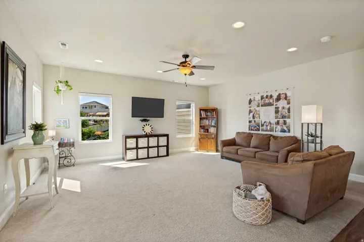 Spacious room featuring neutral carpeting, recessed lighting, and a ceiling fan