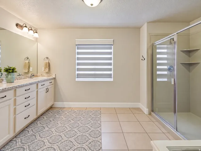 Dual vanity with stone-finish countertop, full-width mirror, and custom cabinetry