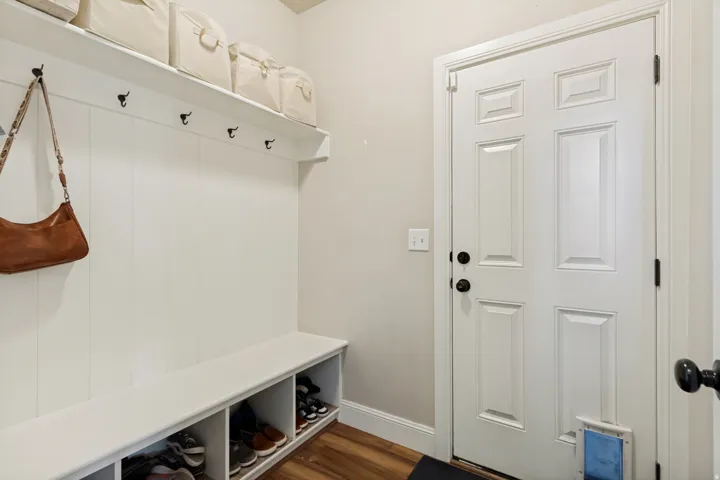 Built-in mudroom bench with cubby storage, vertical paneling, and upper shelving with hooks