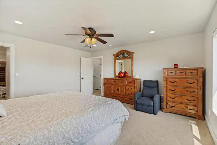 Neutral-toned walls enhance the spacious feel of this room, featuring recessed lighting and a ceiling fan with integrated illumination