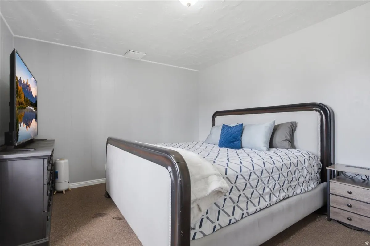 Bedroom featuring light gray walls, textured white ceilings, brown carpeting, and white baseboards