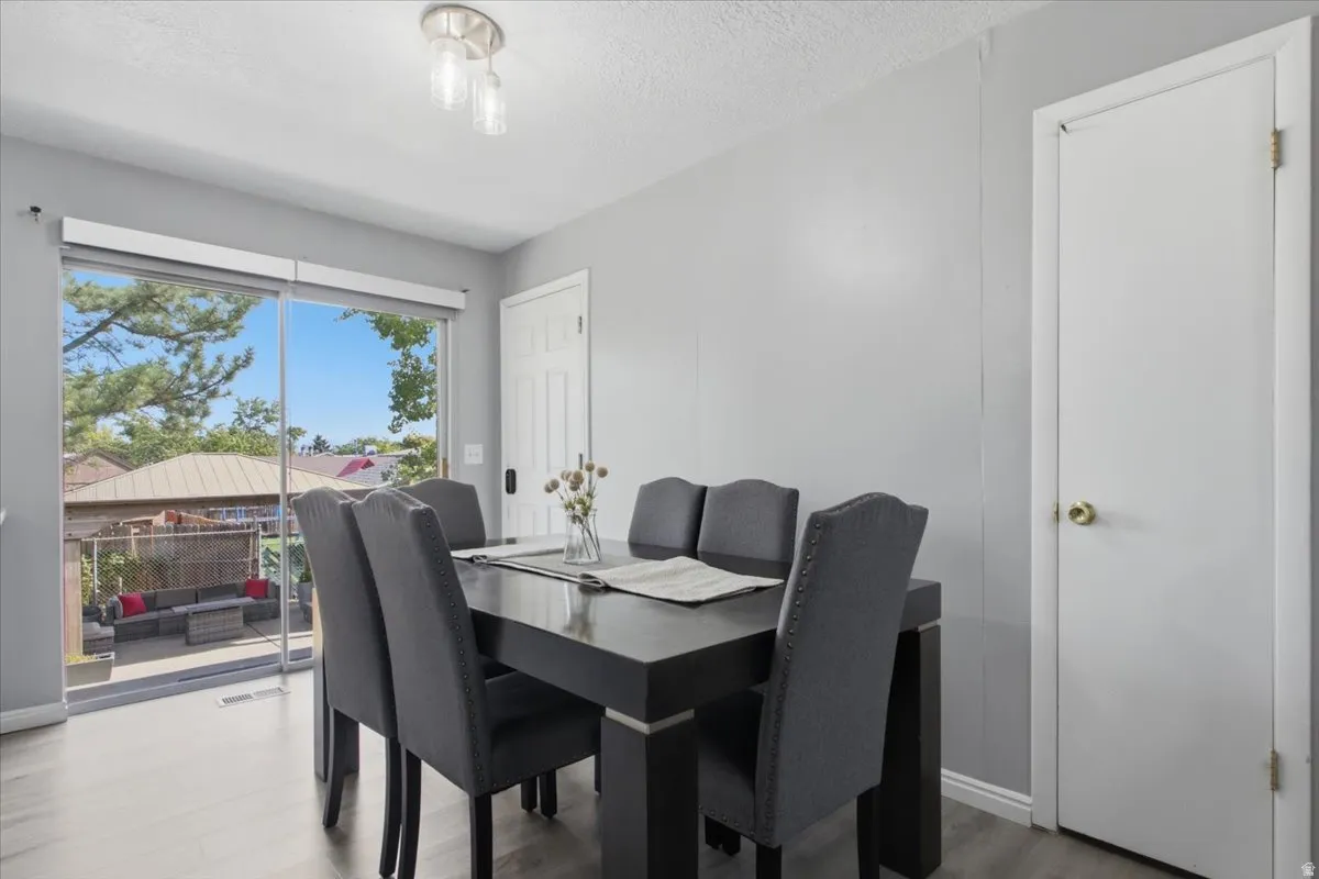 Room with sliding glass door to exterior patio, light gray walls, and wood-finish flooring