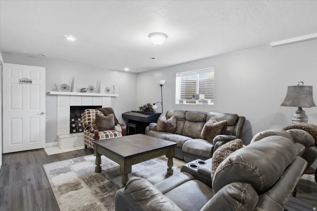 Spacious living area featuring wood-finish flooring, recessed lighting, and a white tile fireplace with a mantel