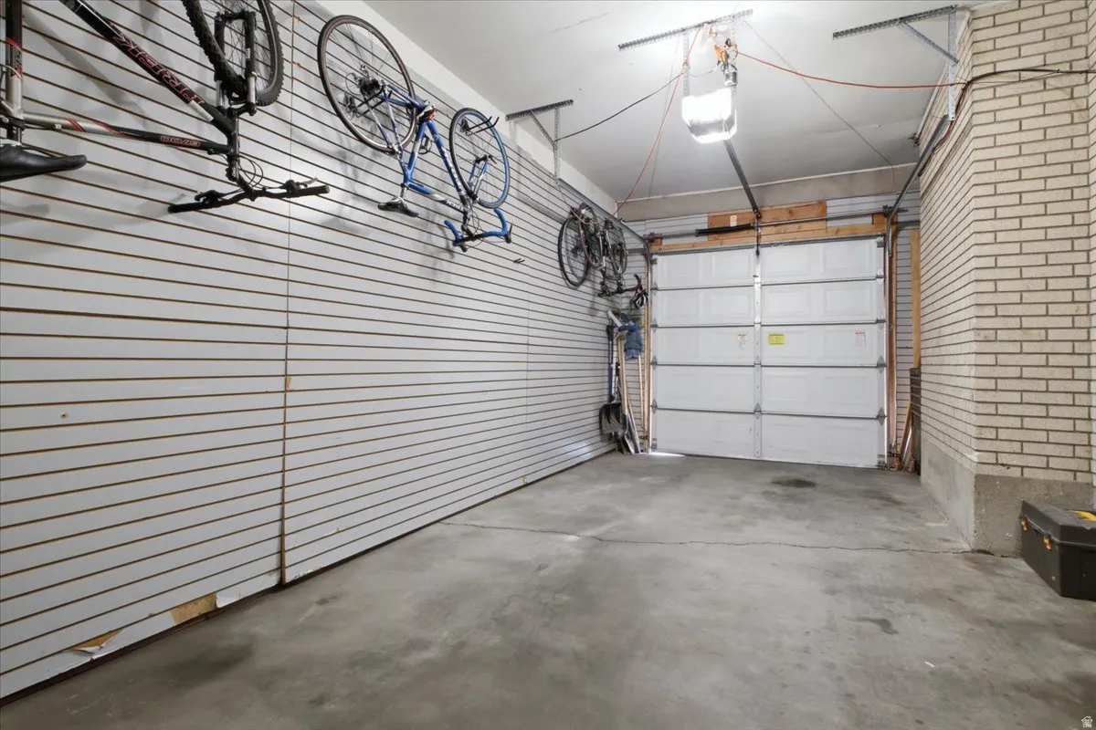 Attached garage with concrete flooring, automatic garage door opener, and slatwall paneling