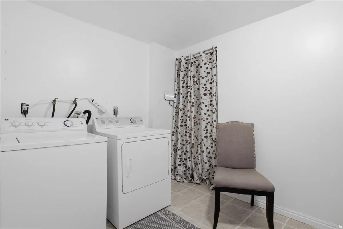 Dedicated laundry area featuring a washer and dryer, tile flooring, and white walls