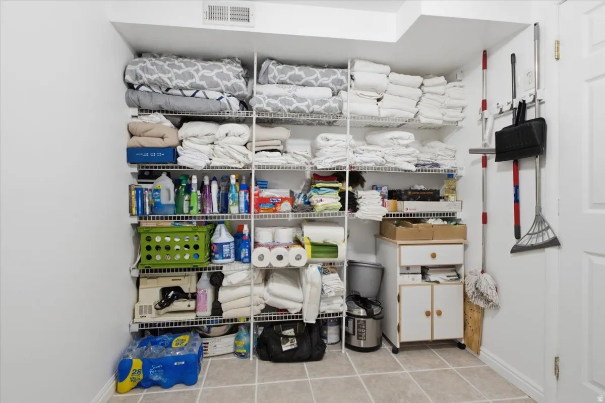 Dedicated storage area featuring wire shelving units, light-toned floor tiles, white walls, and a white door with trim