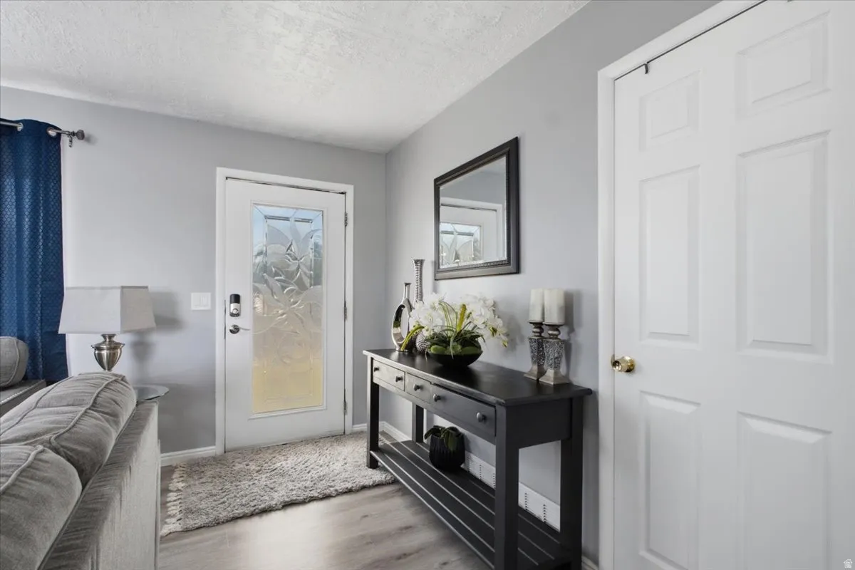 Entryway featuring a decorative glass-paneled door with smart lock hardware, wood-finish flooring, and a paneled interior door