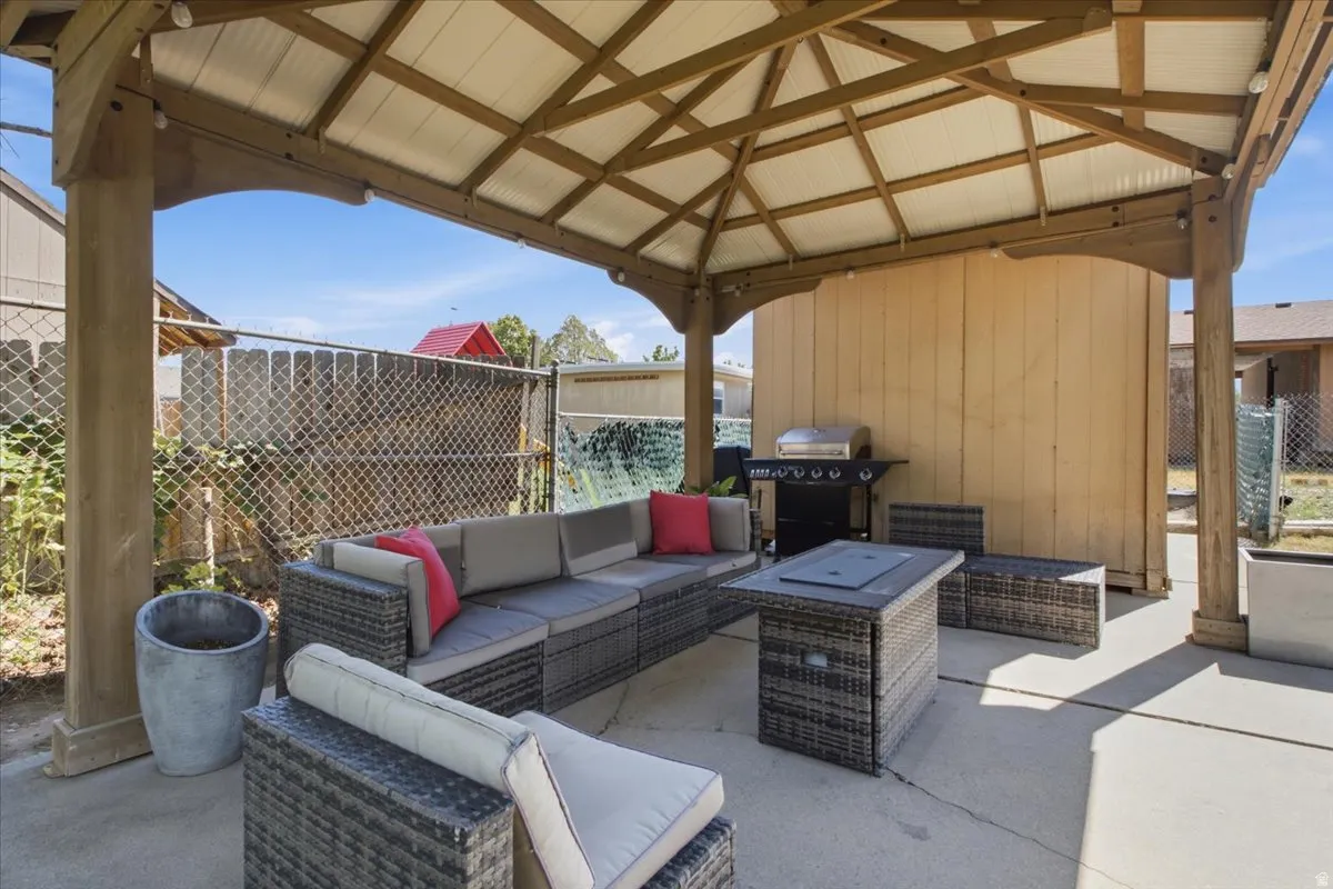 Spacious outdoor patio area featuring a wooden gazebo with a translucent roof, and concrete flooring