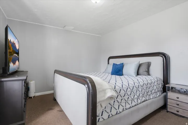 Bedroom featuring light gray walls, textured white ceilings, brown carpeting, and white baseboards