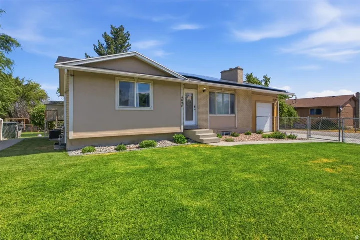 Exterior featuring a light tan stucco finish, concrete front steps, a single-car garage with a white door, and solar panels on the roof