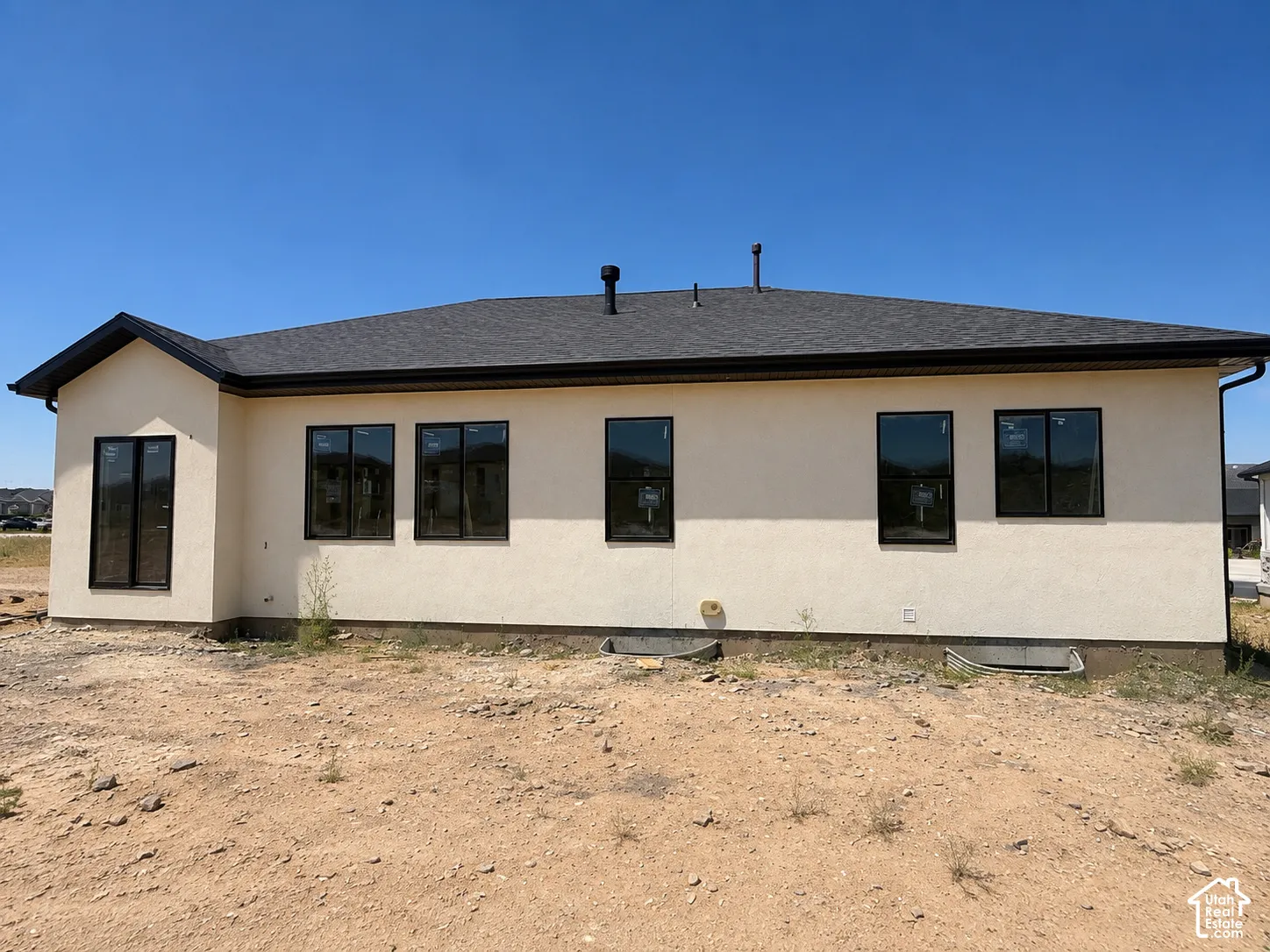 Contemporary stucco exterior with a dark shingle roof and black gutters