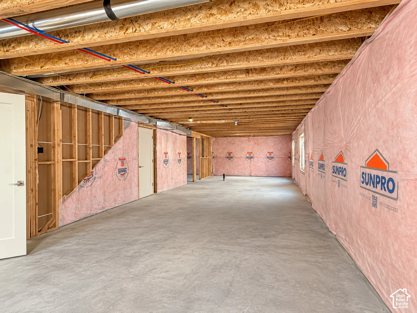 Unfinished interior space featuring exposed wood joist ceilings, concrete flooring, and insulated wall paneling