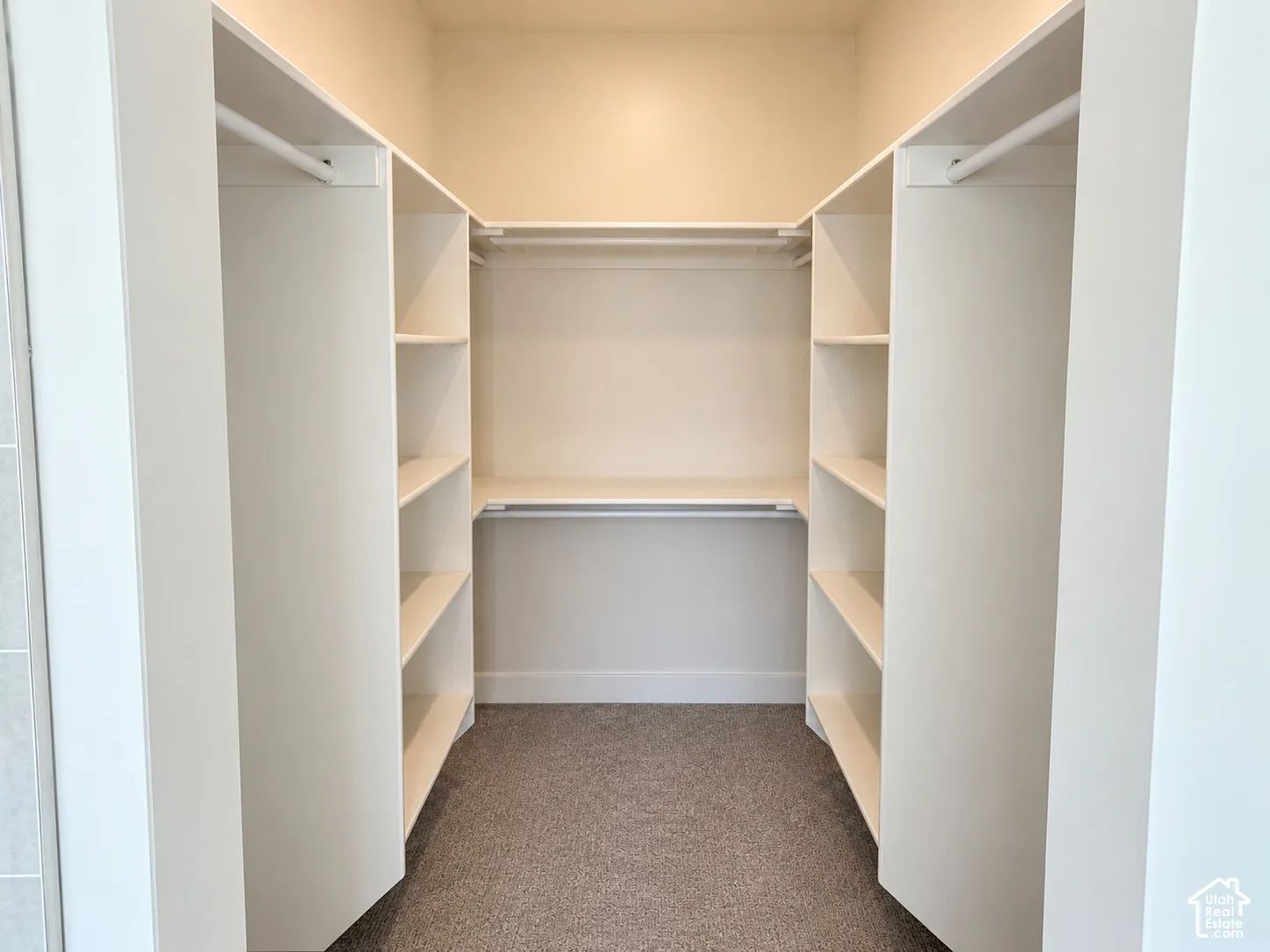 Walk-in closet featuring white built-in shelving, multiple open storage compartments, and integrated horizontal hanging rods