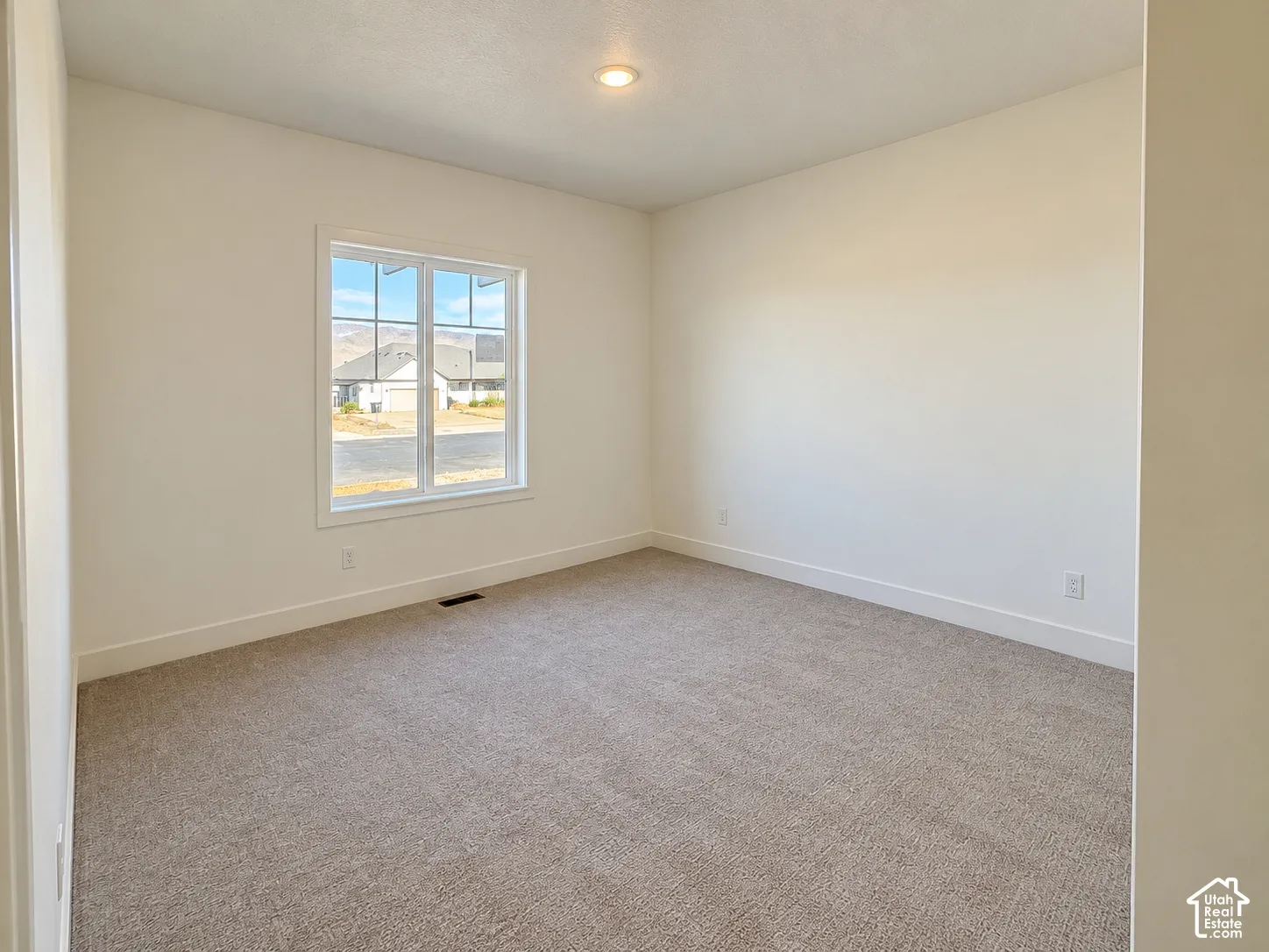 Neutral-toned carpeting, recessed ceiling lighting, and a multi-pane window featuring mountain scenery