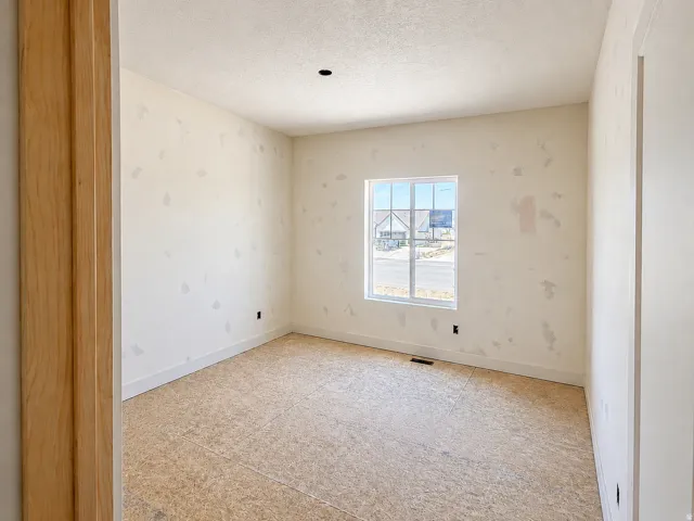 Unfinished room featuring a single window, baseboard trim, and a raw subfloor