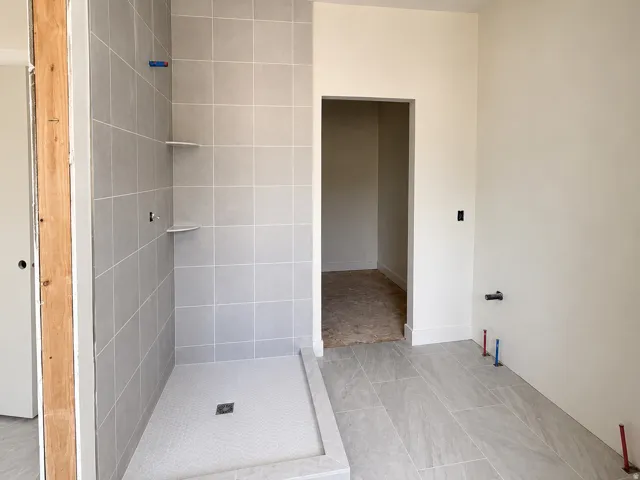 Bathroom showcasing a tiled shower enclosure with built-in shelving and a hexagonal tile floor