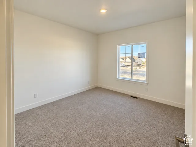 Neutral-toned wall-to-wall carpeting, single-pane window with white trim, and recessed ceiling lighting