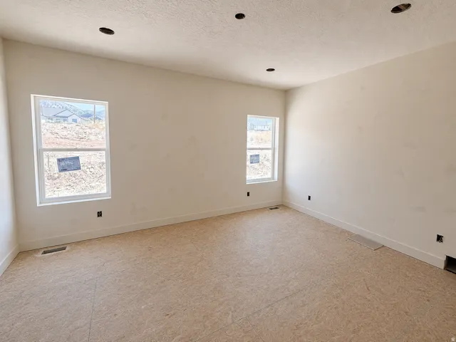 Spacious interior room featuring two windows, recessed ceiling lighting, and primed walls