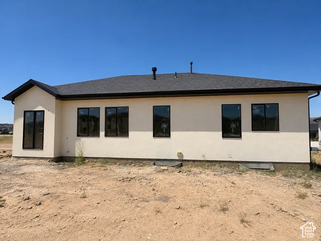 Contemporary stucco exterior with a dark shingle roof and black gutters