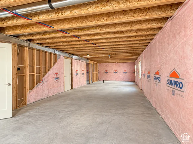 Unfinished interior space featuring exposed wood joist ceilings, concrete flooring, and insulated wall paneling