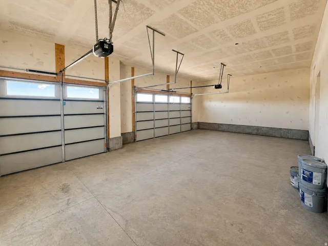 Spacious three-car garage featuring segmented overhead doors with integrated window panels