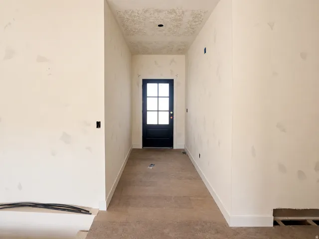 Hallway featuring a black door with glass panels, light-toned walls, and baseboard trim
