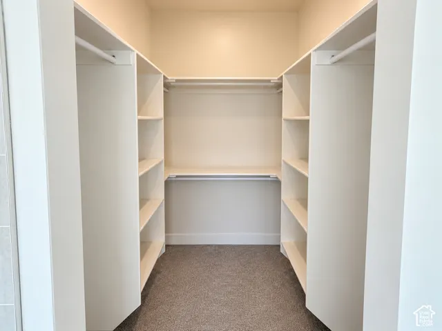 Walk-in closet featuring white built-in shelving, multiple open storage compartments, and integrated horizontal hanging rods