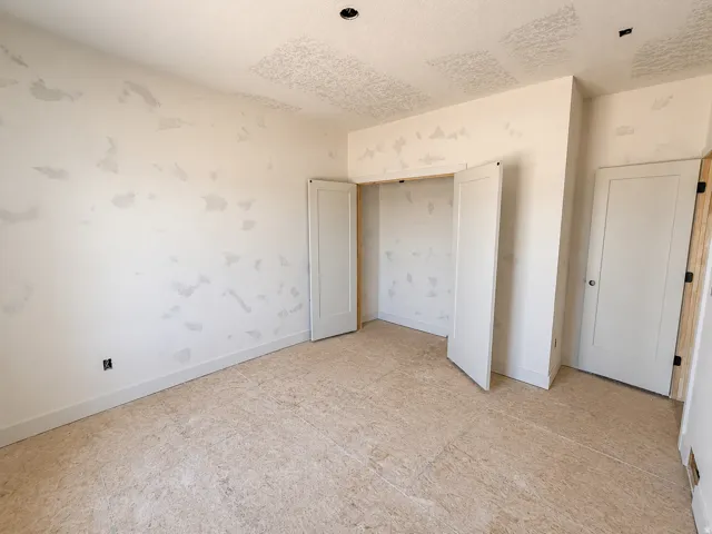 Interior room featuring a textured ceiling, neutral wall tones, and unfinished subflooring