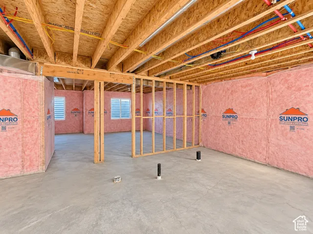 Unfinished lower level featuring concrete flooring, exposed wood ceiling joists, perimeter fiberglass batt insulation, and plumbing rough-ins