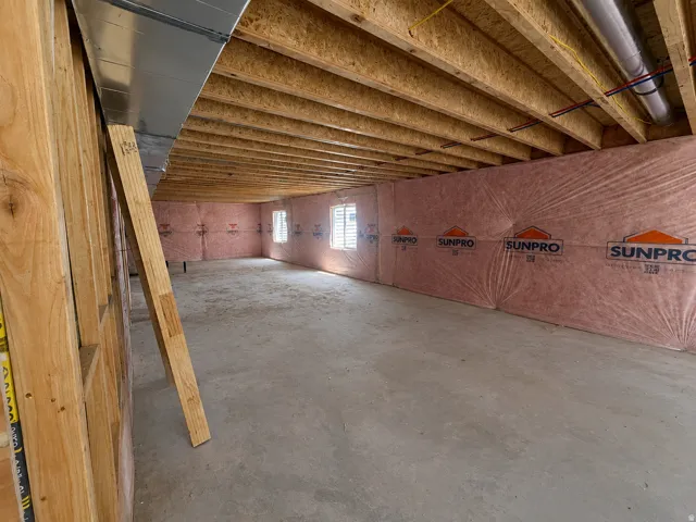 Unfinished basement featuring exposed wood joists, concrete flooring, insulated perimeter walls, and two visible windows