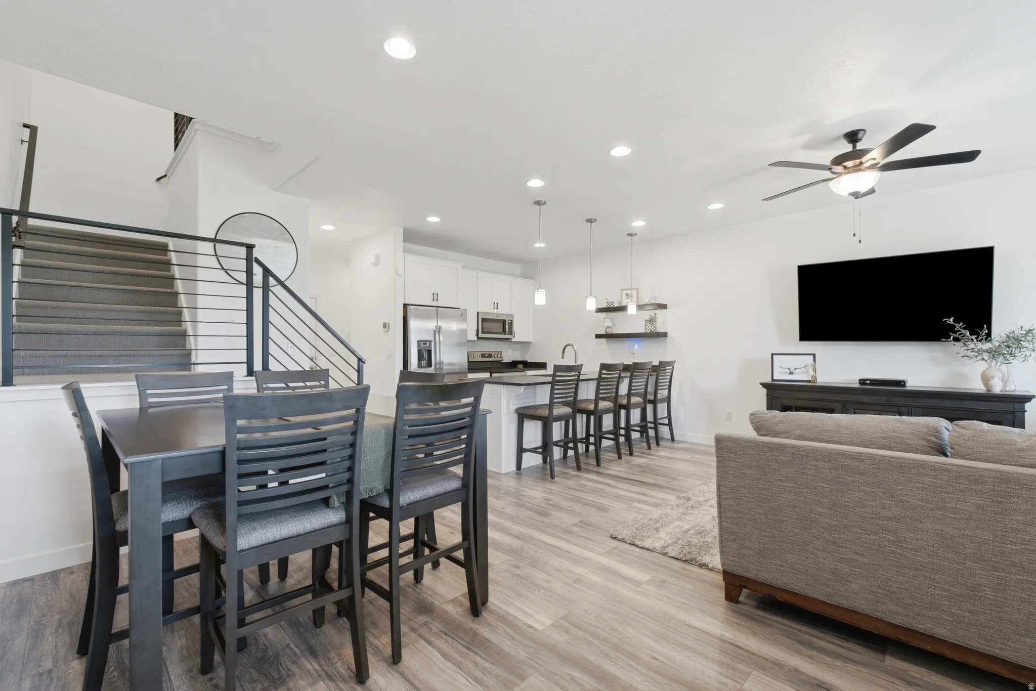 Open-concept living space with wood-finish flooring, recessed lighting, and a contemporary ceiling fan