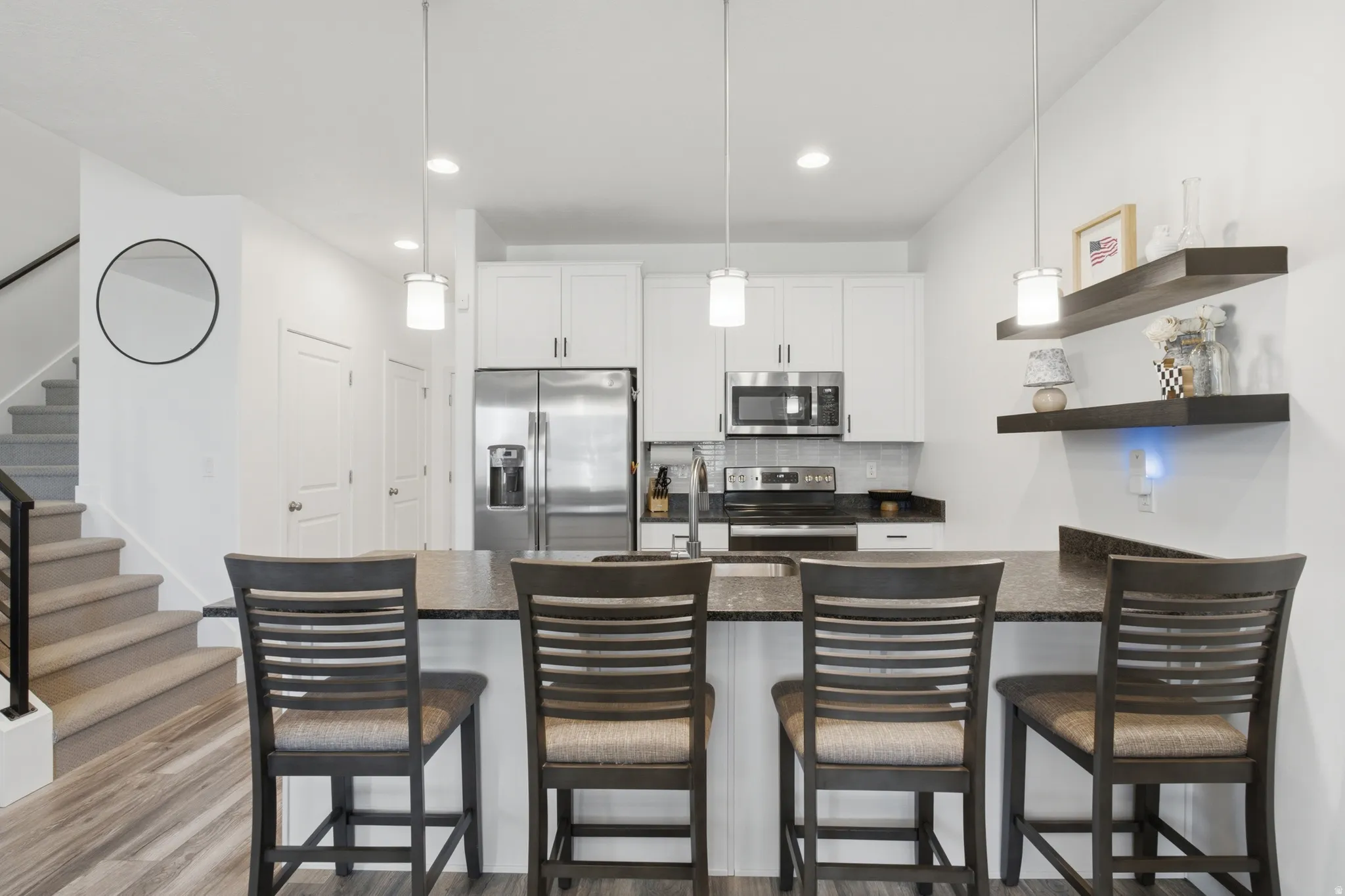 Kitchen featuring white cabinetry, stainless steel appliances, and a dark stone countertop with a breakfast bar