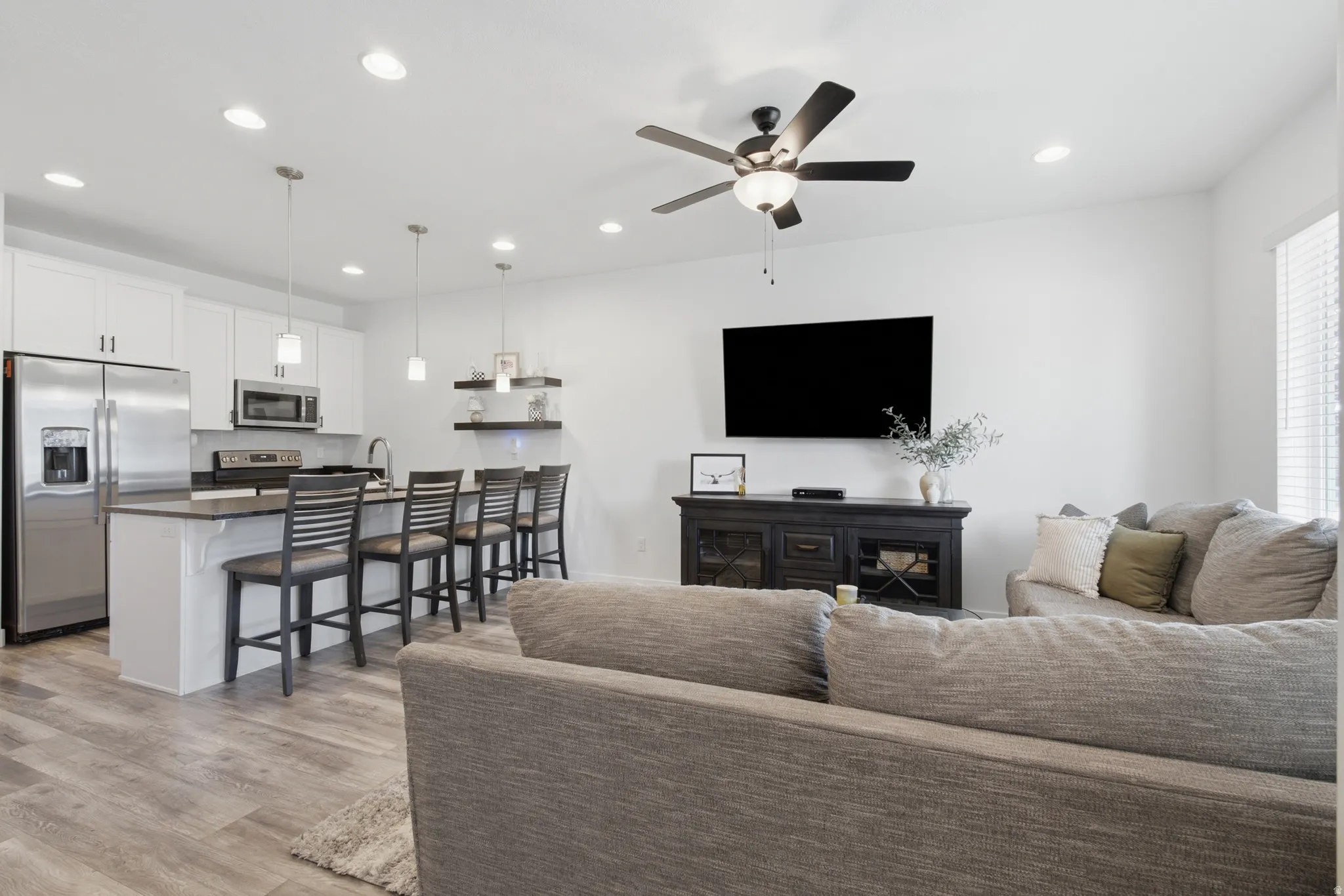 Open-concept living space featuring wood-finish flooring, recessed lighting, and a ceiling fan