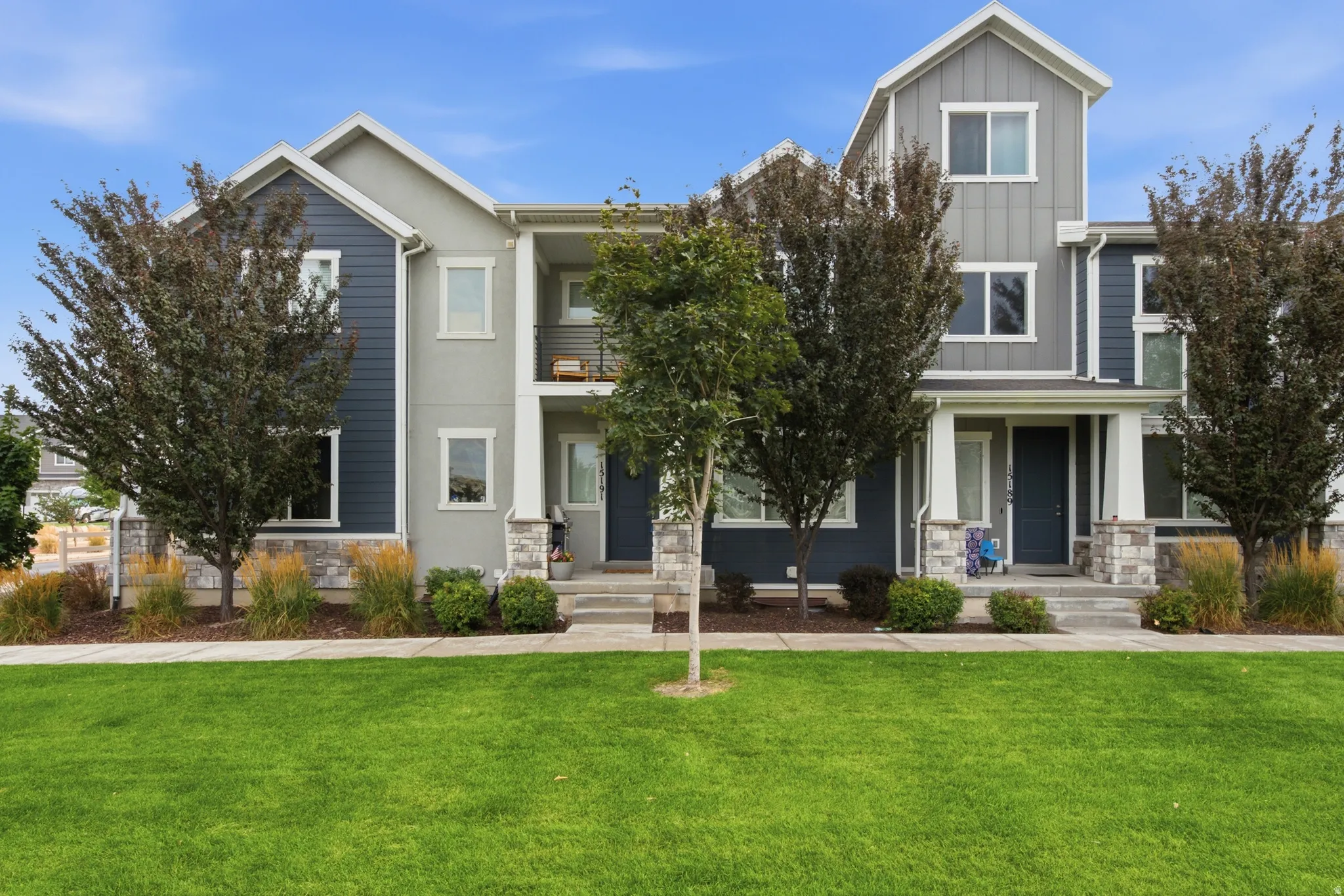 Modern townhome exterior featuring multi-toned siding, gabled rooflines, and a covered entry