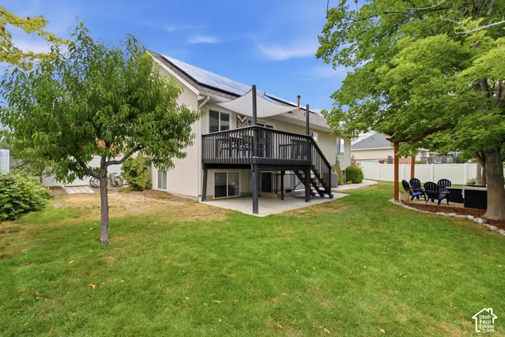 Expansive backyard featuring a multi-level deck with a shade sail, a lower-level patio, and a covered patio area with a pergola.
