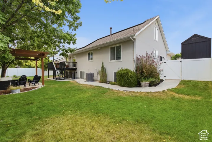 Spacious backyard featuring a pergola-covered patio, elevated deck, full privacy fencing, and a separate storage shed.