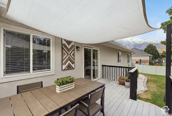 Backyard deck featuring a shade sail, sliding glass door, and black baluster railing.
