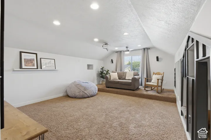 Spacious bonus room featuring vaulted ceilings, recessed lighting, a built-in media projector, and a raised platform.