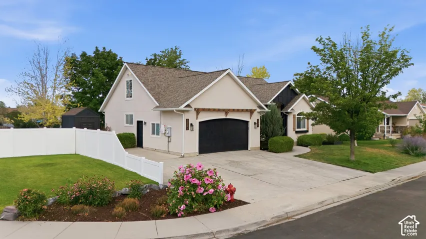 Contemporary stucco residence featuring a dark garage door, complementary dark trim, and a prominent gable roofline.